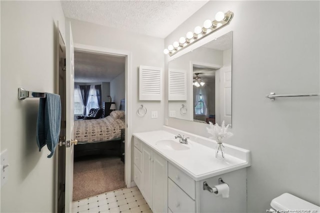 bathroom with toilet, connected bathroom, a textured ceiling, vanity, and tile patterned floors