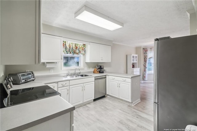 kitchen with a peninsula, stainless steel appliances, a textured ceiling, white cabinetry, and a sink