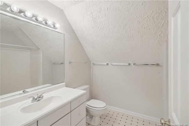 bathroom with toilet, a textured ceiling, vanity, baseboards, and walk in shower