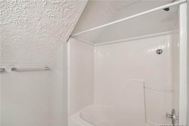 full bathroom featuring a textured wall and shower / tub combination