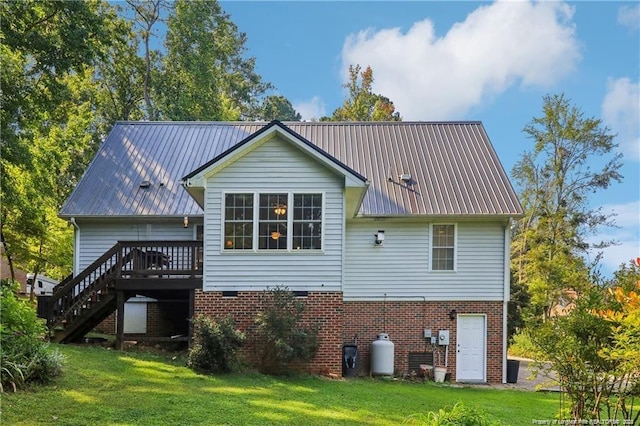 rear view of house featuring a lawn, stairway, metal roof, a deck, and brick siding