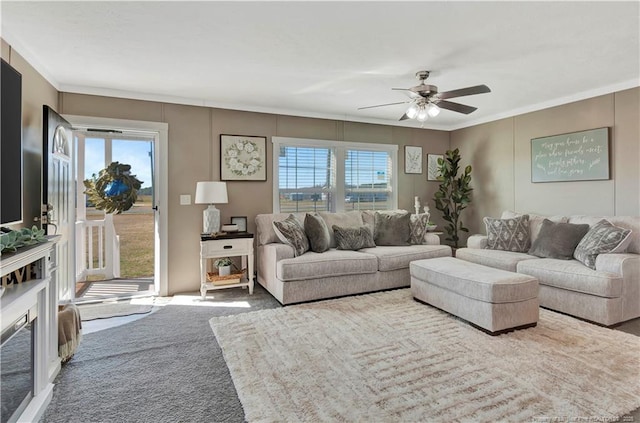 living area with ceiling fan, ornamental molding, and carpet flooring