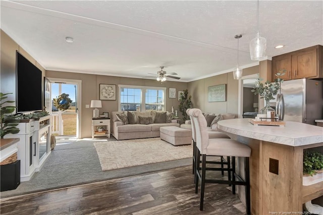 living area featuring dark wood-style floors, a ceiling fan, and crown molding