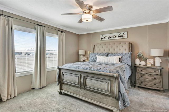 carpeted bedroom featuring a ceiling fan and crown molding