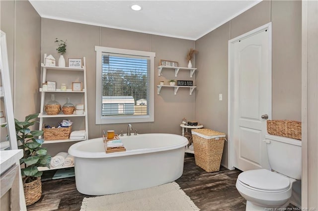 bathroom with toilet, a freestanding bath, ornamental molding, and wood finished floors