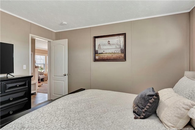 bedroom featuring crown molding, a textured ceiling, and wood finished floors