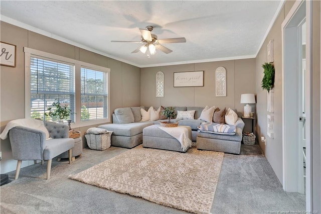 living area with carpet floors, ornamental molding, and ceiling fan