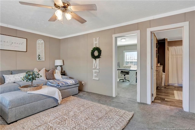 carpeted living room with a textured ceiling, a ceiling fan, and crown molding