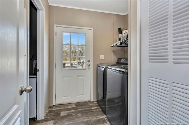 laundry room with laundry area, washing machine and dryer, ornamental molding, and dark wood-type flooring