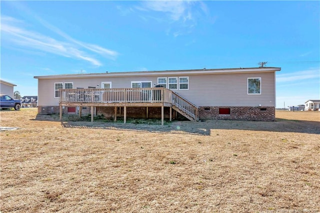 rear view of house with stairway, a lawn, and a deck