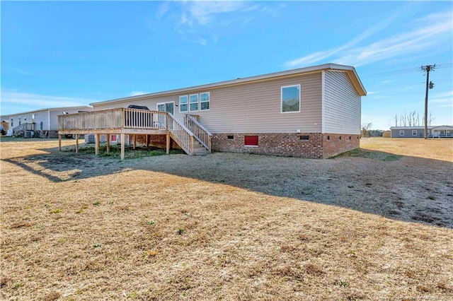 rear view of property with a deck, crawl space, stairs, and a lawn