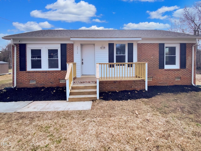 view of front facade with a shingled roof, crawl space, brick siding, and covered porch