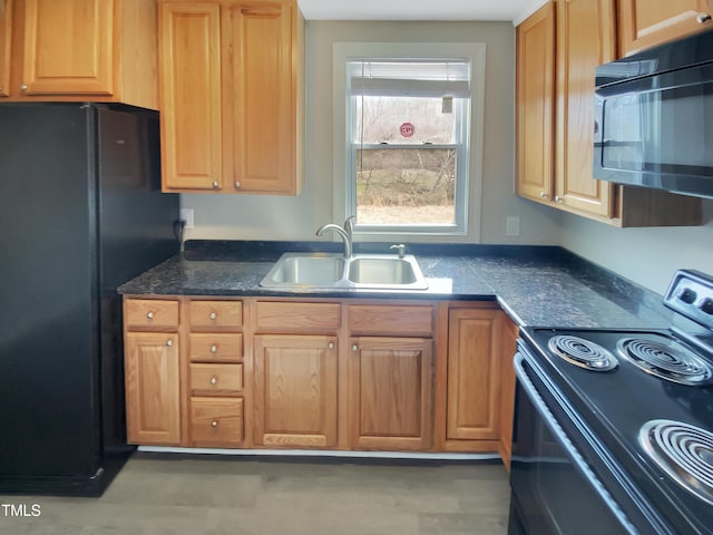 kitchen with dark countertops, black appliances, and a sink