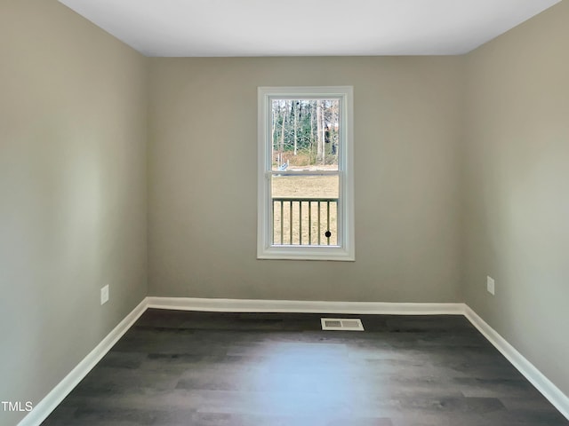 spare room featuring dark wood-style floors, visible vents, and baseboards