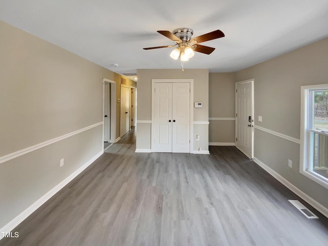 unfurnished bedroom with wood finished floors, visible vents, and baseboards