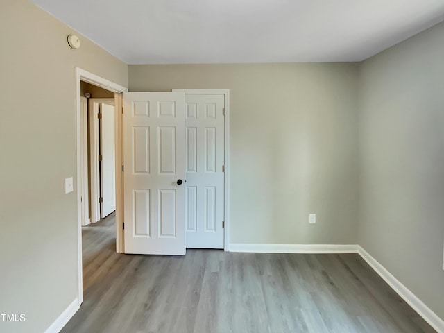 unfurnished bedroom featuring a closet, baseboards, and wood finished floors