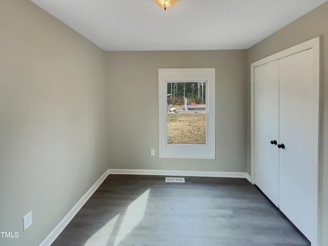 unfurnished bedroom featuring a closet, visible vents, dark wood finished floors, and baseboards