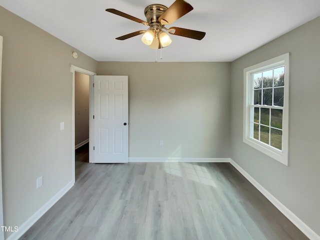 empty room with wood finished floors, a ceiling fan, and baseboards