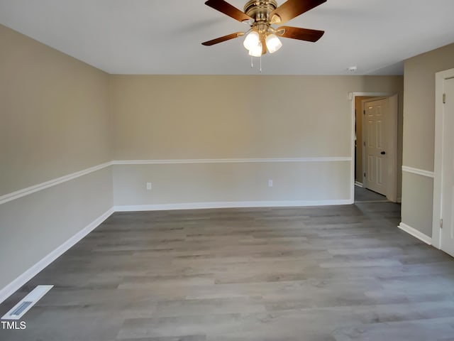 unfurnished room featuring ceiling fan, visible vents, baseboards, and wood finished floors