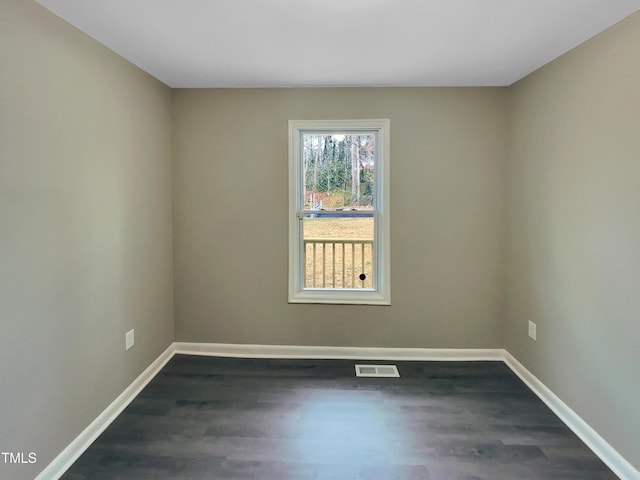 empty room featuring dark wood-style floors, baseboards, and visible vents