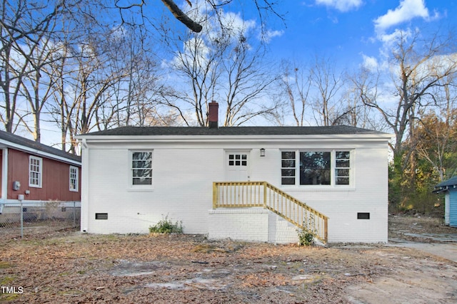 view of front of house featuring brick siding, crawl space, a chimney, and fence