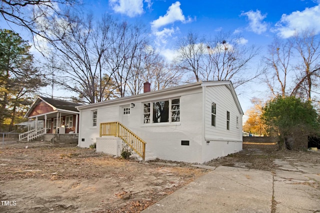 view of front of home featuring crawl space, a chimney, and brick siding