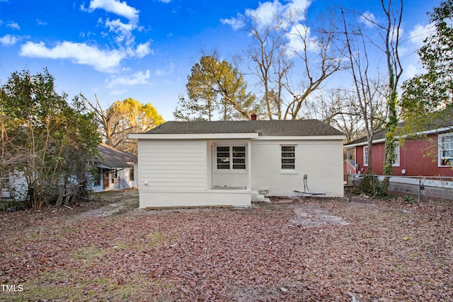 back of house with an outbuilding, brick siding, fence, and a chimney