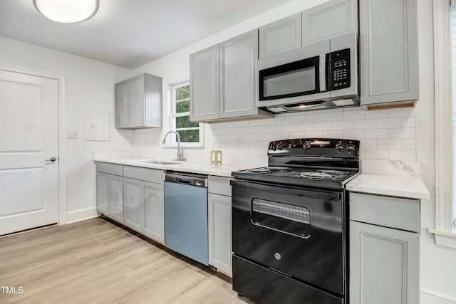 kitchen featuring dishwashing machine, gray cabinetry, a sink, black electric range, and stainless steel microwave