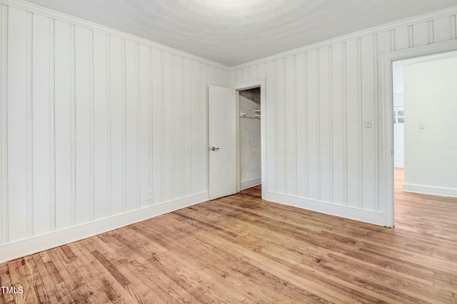 spare room featuring baseboards, wood finished floors, and crown molding