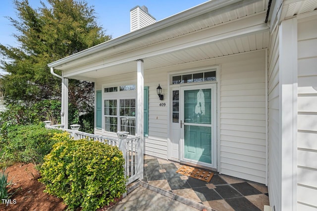 property entrance with covered porch and a chimney