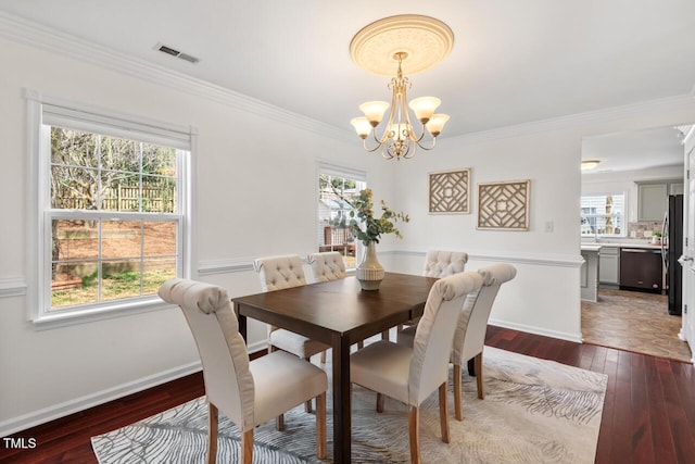 dining room with hardwood / wood-style flooring, a healthy amount of sunlight, visible vents, and a chandelier