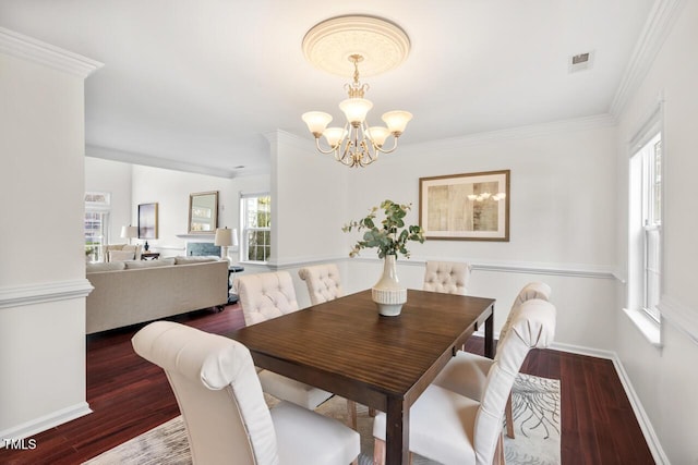 dining space with crown molding, a notable chandelier, wood finished floors, and baseboards