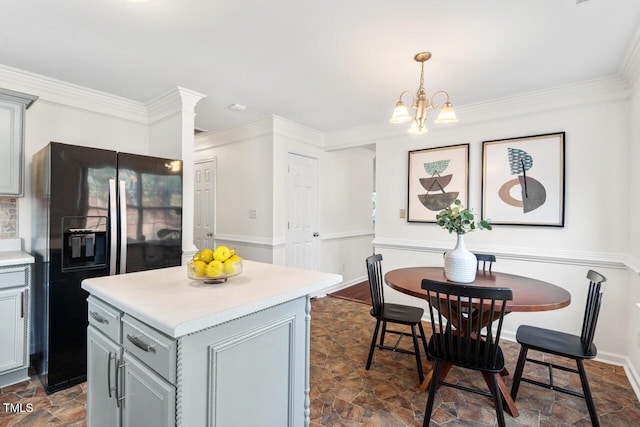 kitchen with gray cabinets, light countertops, stone finish flooring, crown molding, and black refrigerator with ice dispenser