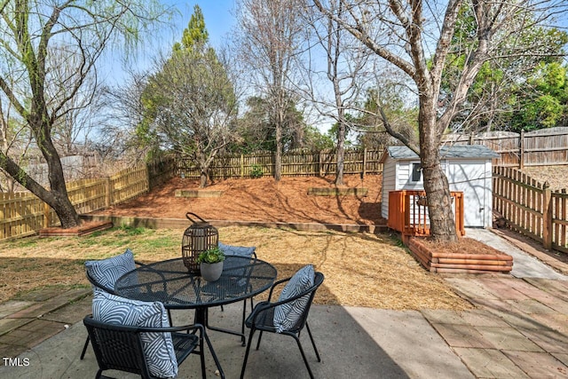 view of patio with a fenced backyard, outdoor dining area, a storage shed, and an outdoor structure