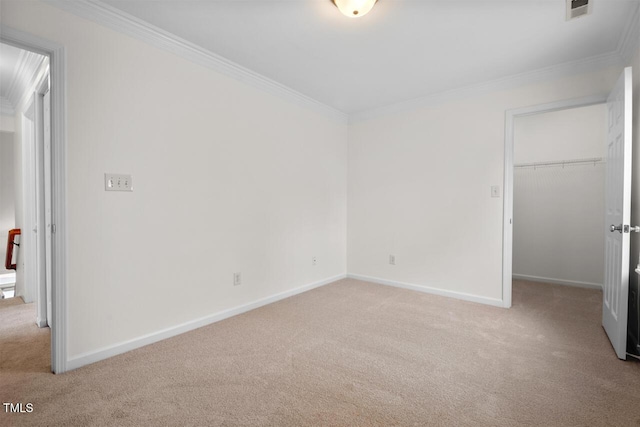 unfurnished bedroom with visible vents, light carpet, a walk in closet, ornamental molding, and baseboards