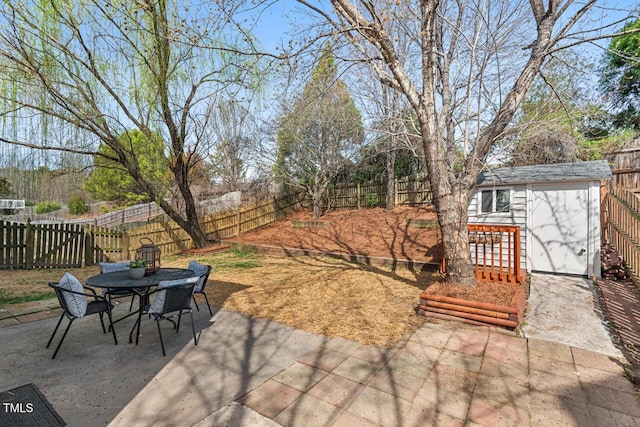 view of patio featuring outdoor dining area, an outbuilding, a fenced backyard, and a shed