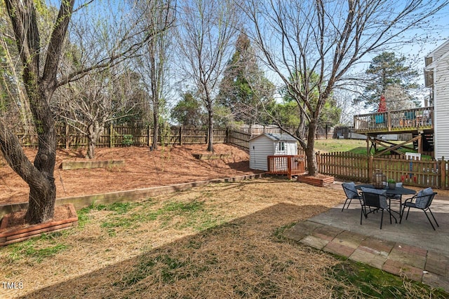 view of yard with a fenced backyard, a wooden deck, an outdoor structure, and a patio area