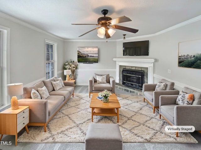 living room featuring ornamental molding, ceiling fan, a tiled fireplace, and wood finished floors