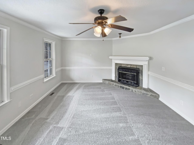 unfurnished living room with visible vents, baseboards, a fireplace with raised hearth, crown molding, and carpet flooring