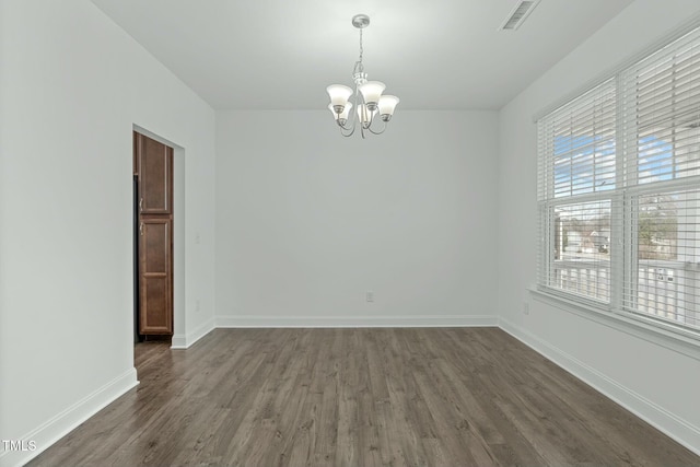 empty room featuring dark wood-style flooring, visible vents, a notable chandelier, and baseboards