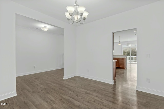 unfurnished dining area with an inviting chandelier, baseboards, and dark wood finished floors