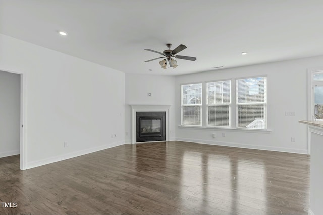 unfurnished living room with a glass covered fireplace, dark wood-style flooring, baseboards, and recessed lighting