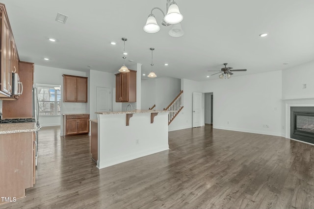 kitchen with a glass covered fireplace, visible vents, appliances with stainless steel finishes, brown cabinets, and a kitchen bar