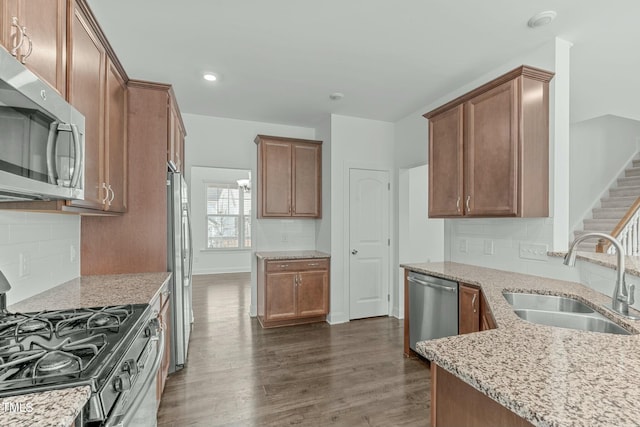 kitchen featuring tasteful backsplash, dark wood finished floors, appliances with stainless steel finishes, light stone countertops, and a sink