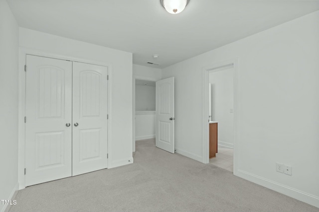 unfurnished bedroom with light carpet, visible vents, baseboards, connected bathroom, and a closet