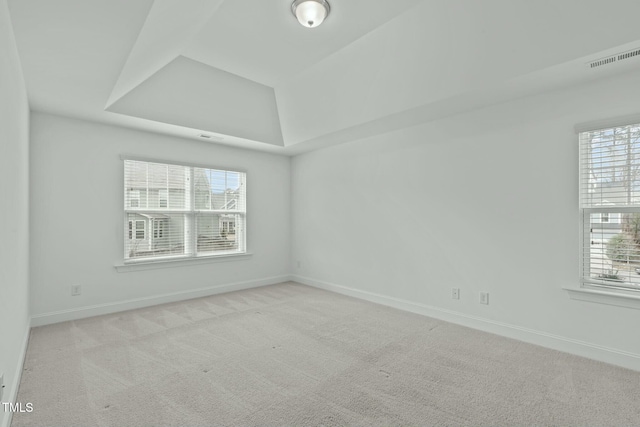 empty room with carpet, visible vents, baseboards, and a raised ceiling