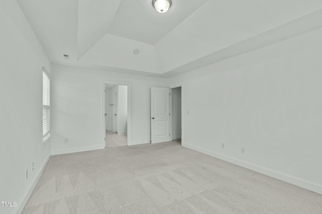 unfurnished bedroom with a tray ceiling, carpet flooring, and baseboards