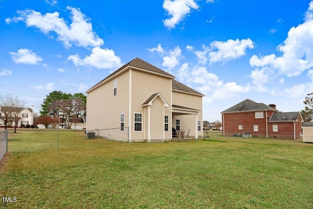 rear view of property with central AC, fence, and a lawn