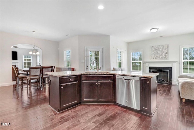 kitchen with dark wood finished floors, a fireplace, stainless steel dishwasher, open floor plan, and a sink