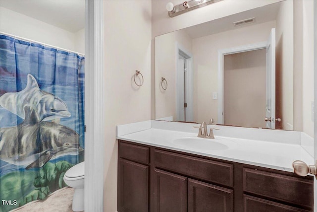 bathroom with toilet, vanity, and visible vents